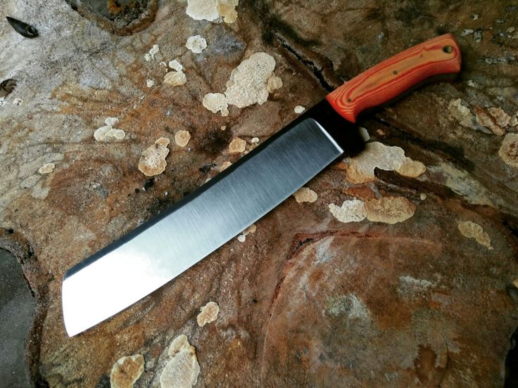 a large knife laying on top of a rock next to some dirt and rocks in the background