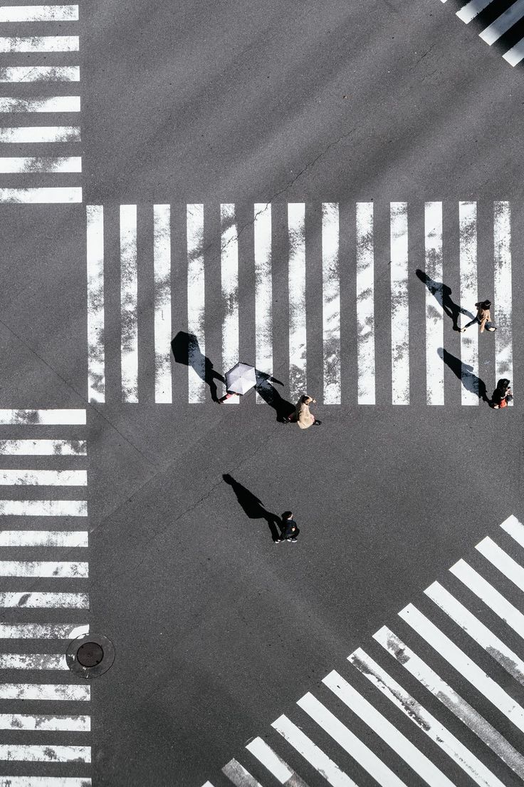 an overhead view of people walking across a crosswalk in the middle of a street