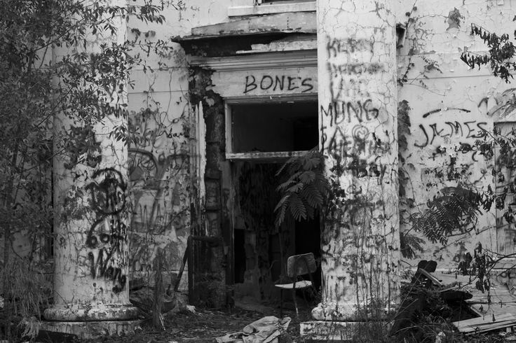 an old building with graffiti all over it's walls and door that says bones