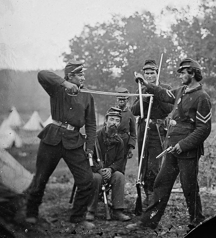 an old black and white photo of men in uniforms with baseball bats on their shoulders