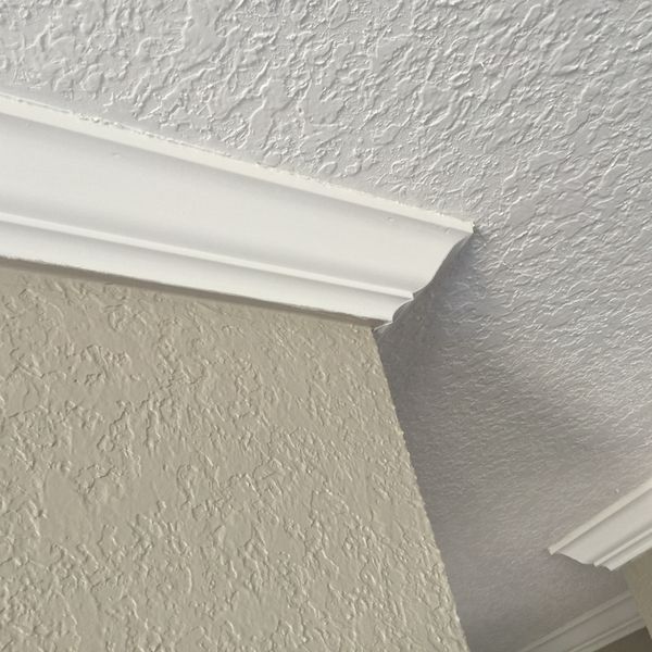 the corner of a room with white paint and molding on the wall above it