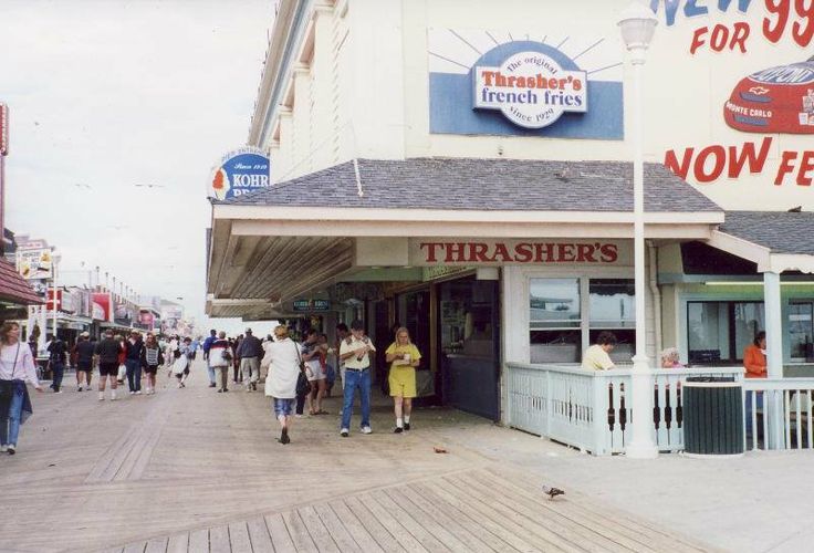 there are many people walking on the boardwalk in front of this restaurant that is now closed