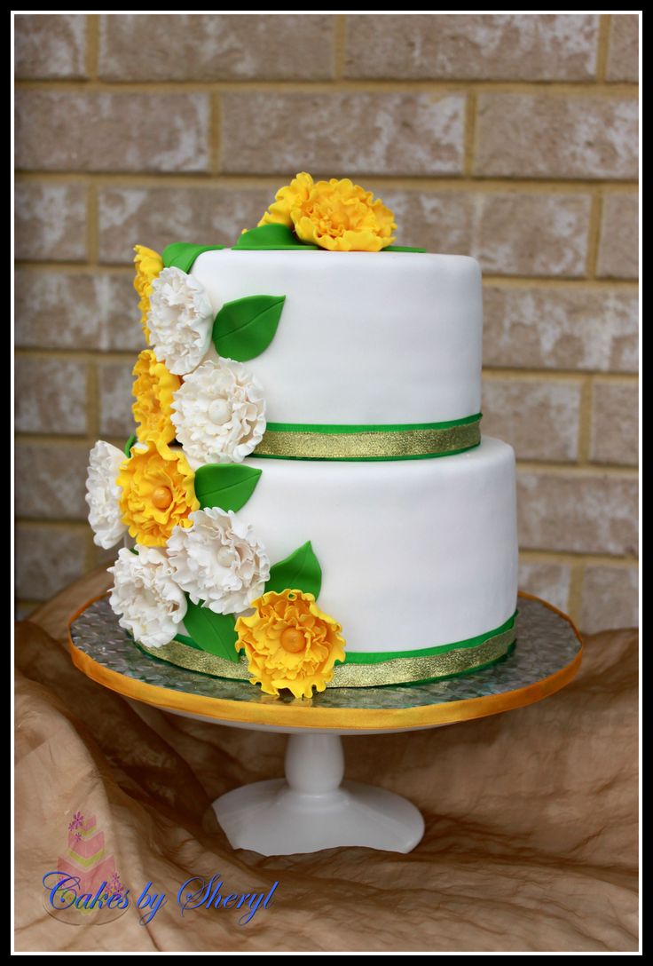 a three tiered cake with yellow and white flowers