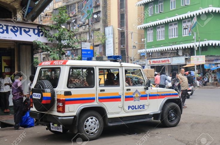 a police car parked in front of a building with people standing on the side walk