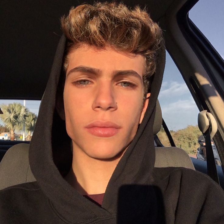 a young man sitting in the back seat of a car wearing a black hoodie