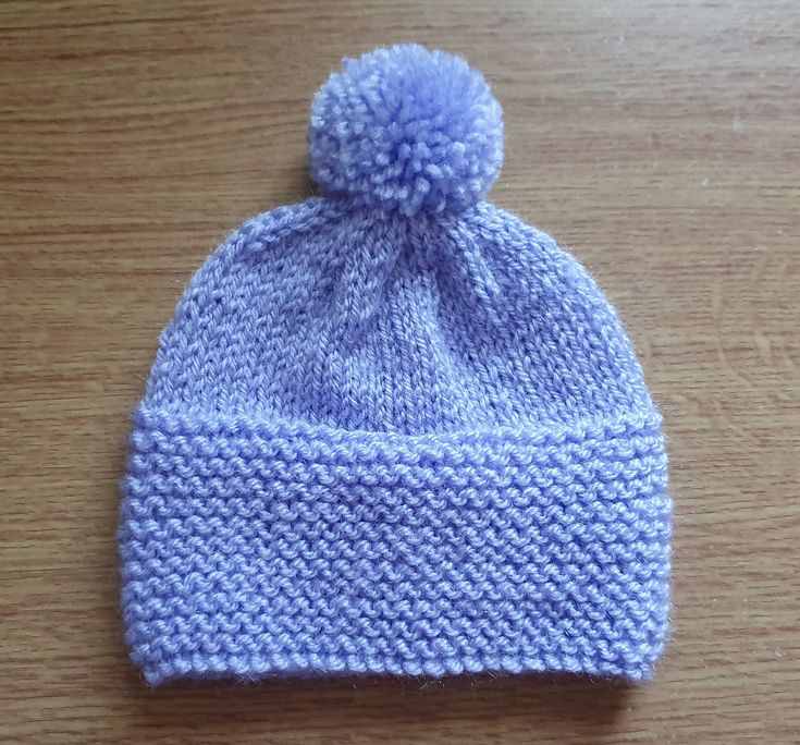 a blue knitted hat sitting on top of a wooden table