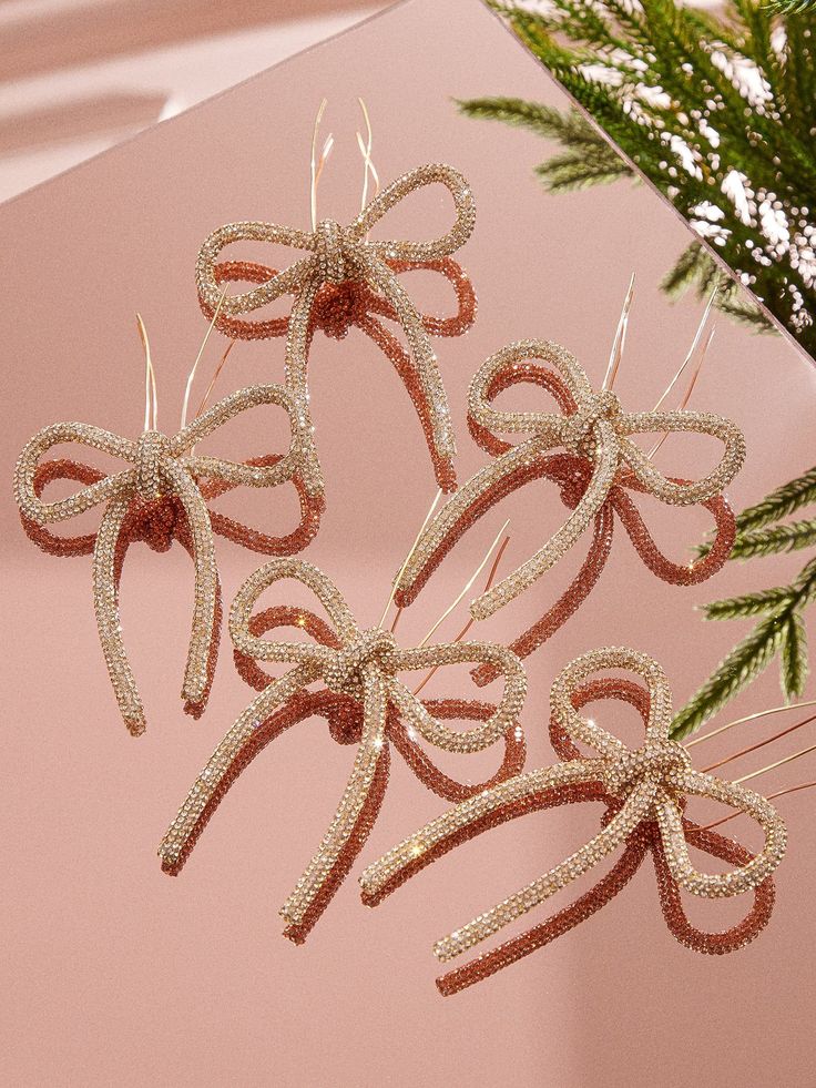 three bows are hanging from the side of a christmas tree ornament on a pink background