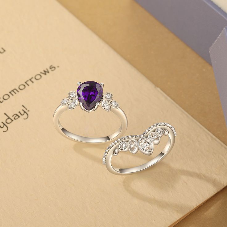 two silver rings with an amethyst purple stone in the middle on top of a card