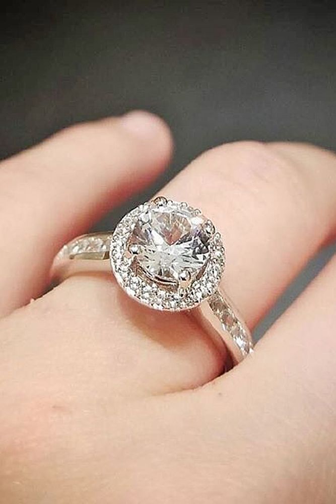 a close up of a person's hand holding a diamond ring