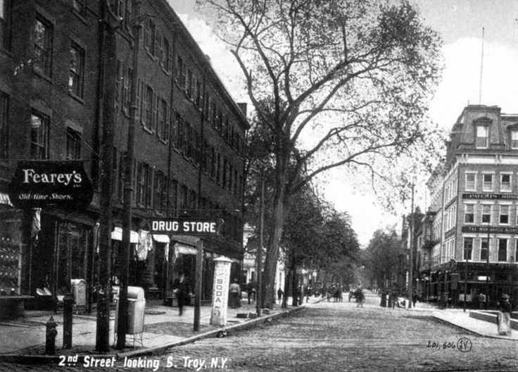 an old black and white photo of people walking down the street in front of buildings