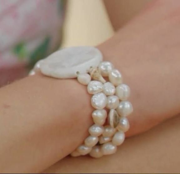 a close up of a woman's arm with pearls on it