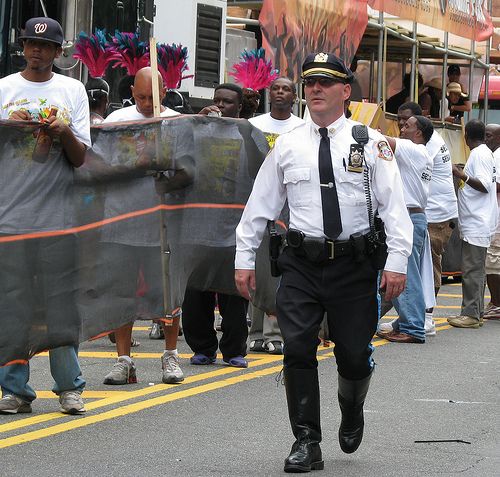 a police officer is walking down the street in front of other people and some are holding flags