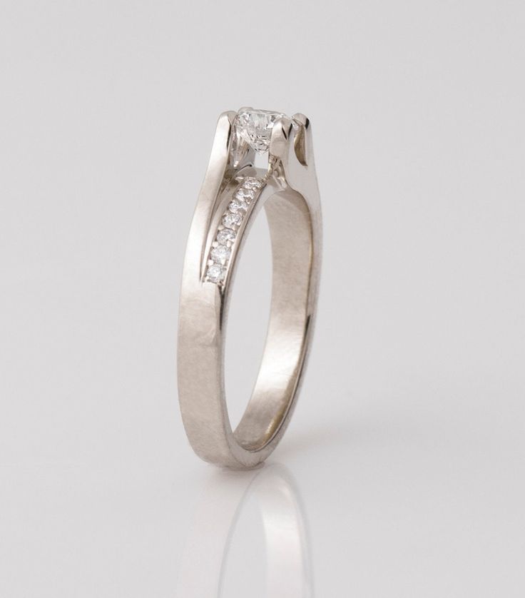 a white gold engagement ring with two princess cut diamonds on the side and channeled band