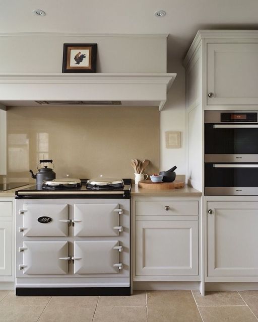 an old fashioned stove and oven in a white kitchen with beige tile flooring on the walls