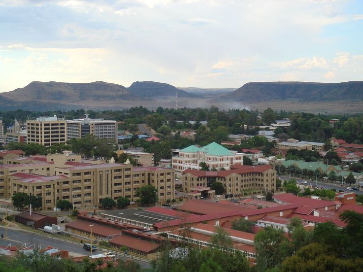 an aerial view of a city with mountains in the background and trees