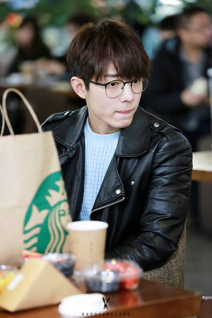 a young man sitting at a table with a starbucks bag on it's lap