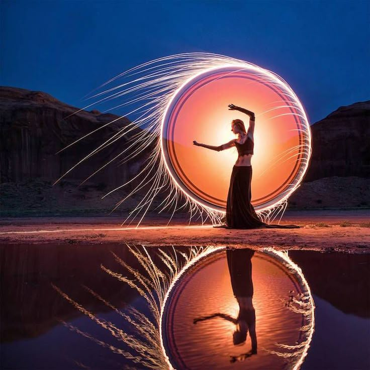 a woman standing in front of a body of water holding a spinning disk with her hands