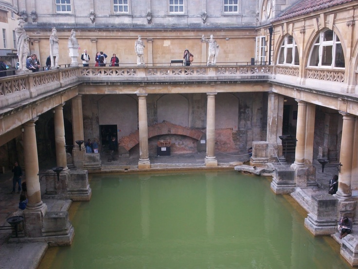 people are standing in the middle of a building with green water and stone steps leading up to it