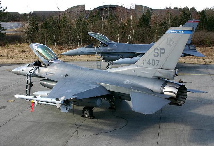 two fighter jets sitting on top of an airport tarmac