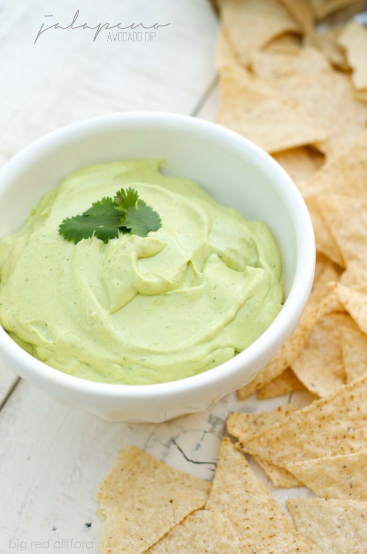 a white bowl filled with guacamole surrounded by tortilla chips