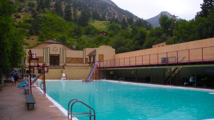 an empty swimming pool in front of a building with mountains in the backgroud