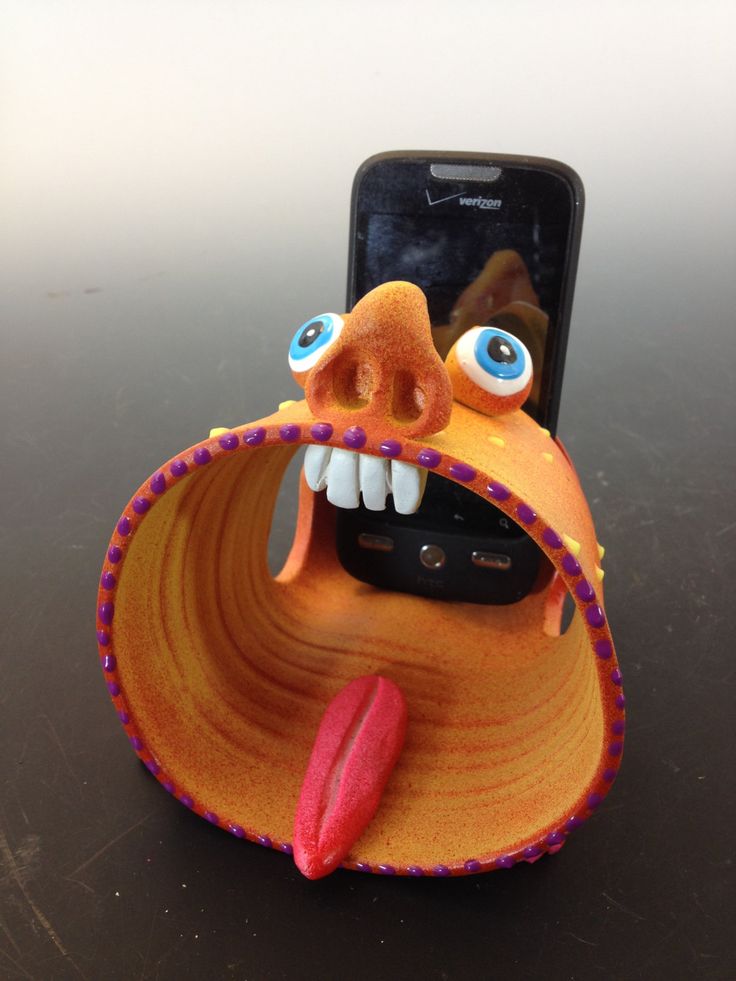 a cell phone holder made to look like an orange monster with its mouth open and tongue out