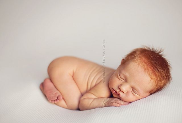 a baby sleeping on its side with his eyes closed