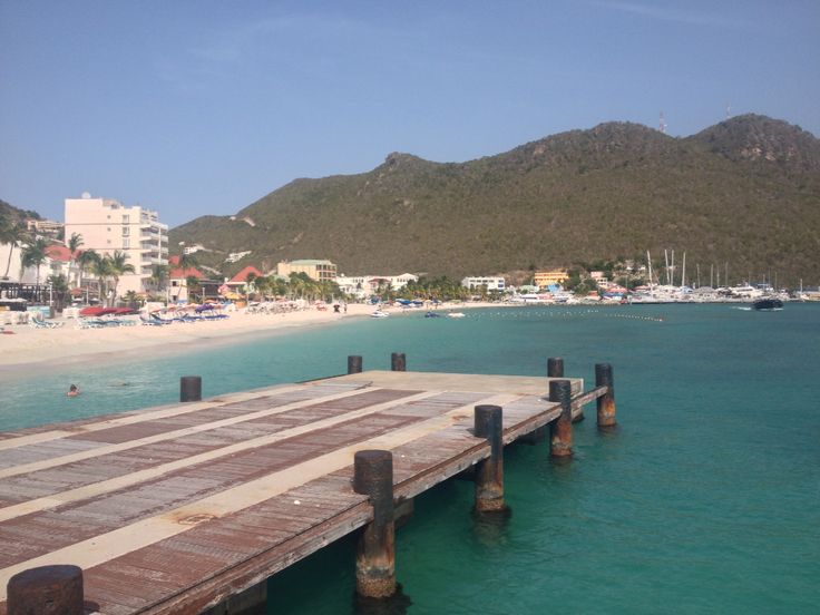 a wooden dock sitting on top of a body of water next to a sandy beach