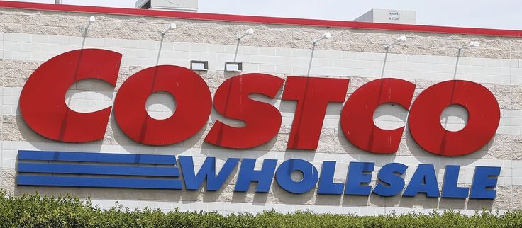 the costco whole sale sign in front of a building with bushes and shrubs around it