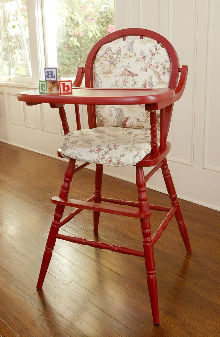 a red wooden chair sitting on top of a hard wood floor next to a window