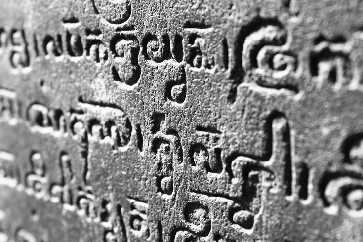 the word buddha written in buddhist writing on a stone wall with other words and symbols