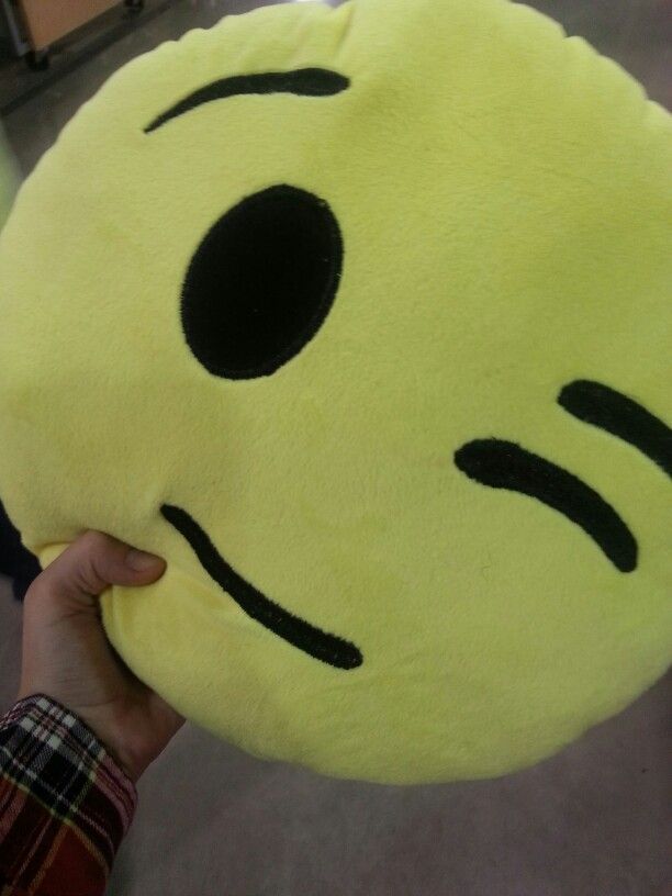 a person holding a yellow pillow with black eyes and nose drawn on it's face