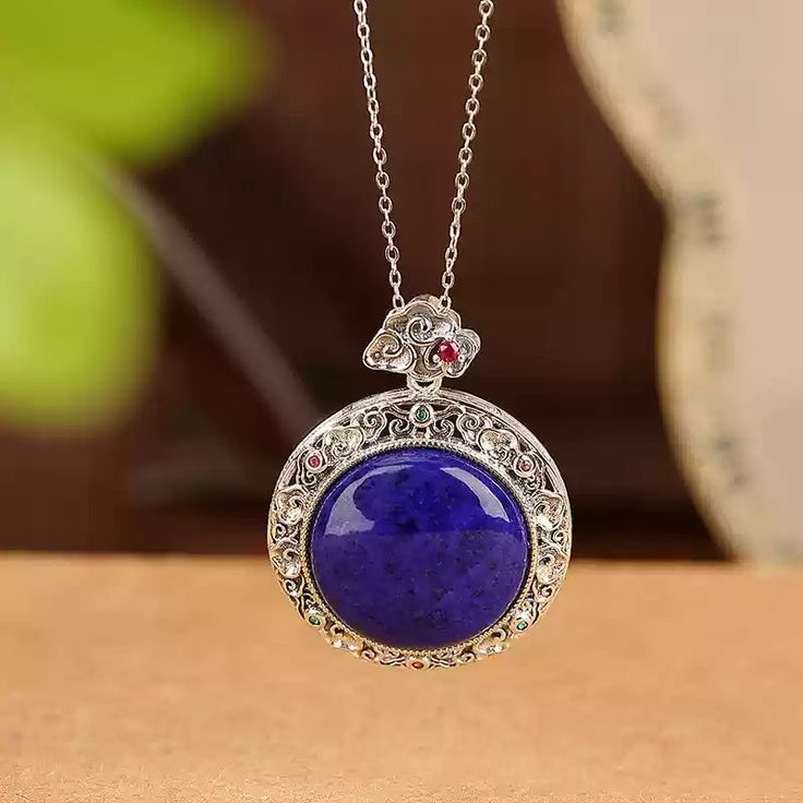 Material: S925 Sterling Silver with Gold PlatingGemstone: Lapis Lazuli, approximately 20mmWeight: Approximately 8.5gSize: Pendant Diameter: 28mm, Total Length: 36mm Description:This Lapis Lazuli Pendant Necklace showcases the captivating deep blue hue of a 20mm natural lapis lazuli gemstone, set in an intricately designed gold-plated S925 sterling silver frame. The ornate detailing around the pendant adds a vintage-inspired elegance, while the addition of colorful accent stones enhances its allure. The necklace's refined chain complements the pendant, creating a balanced, eye-catching piece. Perfect for adding a pop of color and a touch of sophistication to any outfit, this necklace is a must-have for lovers of unique and timeless jewelry. Note: The natural properties and composition of mi Sapphire Jewelry With Gemstone Accents, Sapphire Jewelry With Natural Stones For Gift, Gift Sapphire Jewelry With Natural Stones, Sterling Silver Crystal Necklace With Natural Stones, Spiritual Sterling Silver Necklace With Round Stone, Spiritual Silver Necklace With Gemstone Accents, Spiritual Silver Necklaces With Gemstone Accents, Sapphire Gemstone Round Pendant Jewelry, Silver Crystal Pendant Necklace With Gemstone Accents