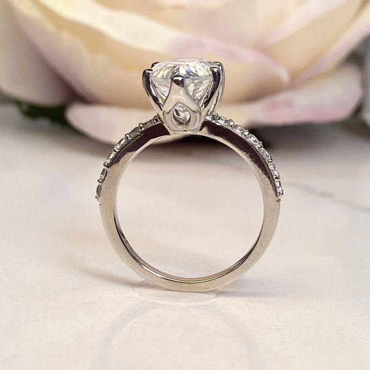 a diamond ring sitting on top of a white flower