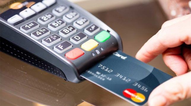 a person holding a credit card in front of an atm machine