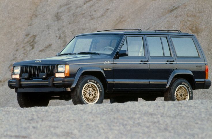 a black suv parked on top of a sandy beach next to a mountain side covered in sand