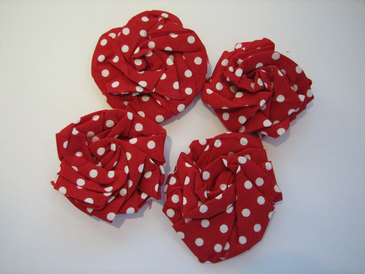 four red and white polka dot fabric flowers on a white surface with one flower in the center