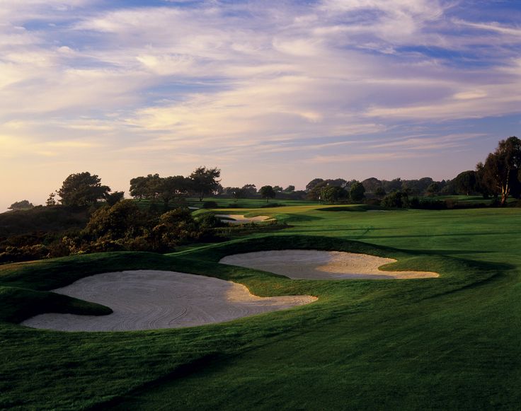 a golf course with sand bunkers and green grass