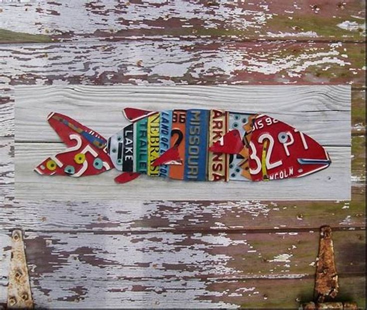 a fish made out of different types of magnets on a wooden planked wall