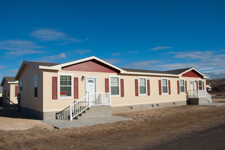 a mobile home sits in the middle of a dirt lot with stairs leading up to it