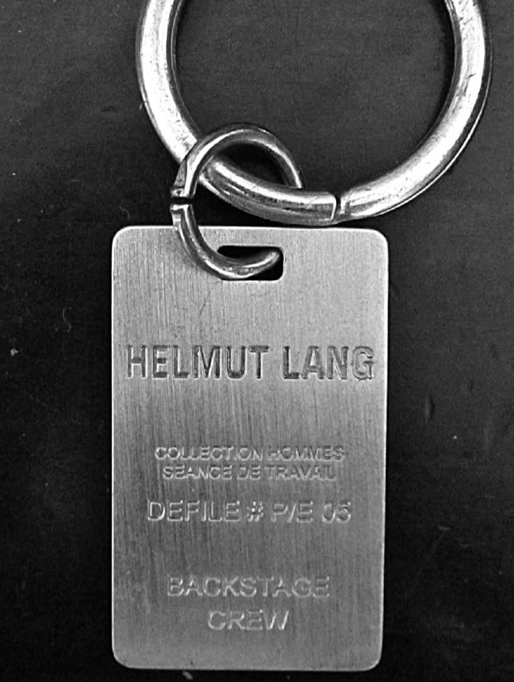 a metal keychain with the words helmut lang on it's side