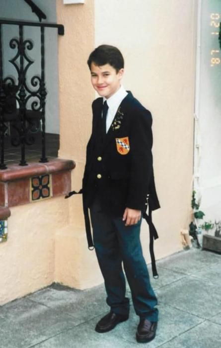 a young boy in uniform standing next to a building