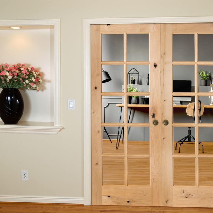 a vase filled with flowers sitting on top of a wooden floor next to two doors