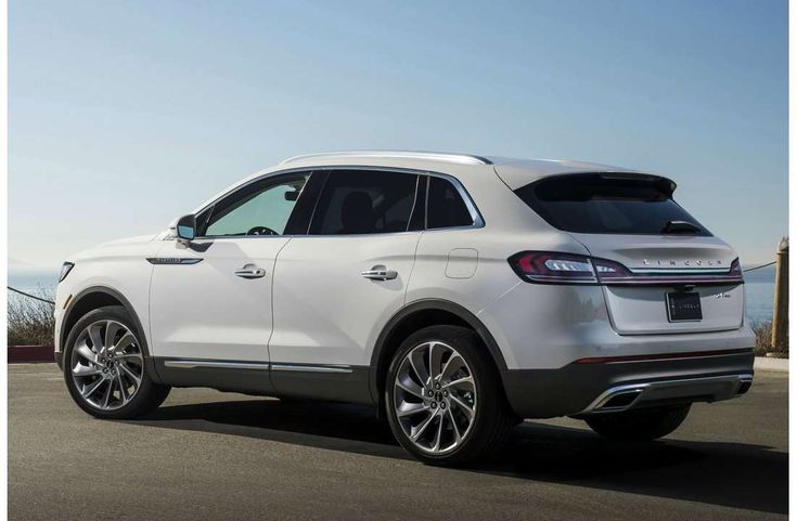 the rear end of a white suv parked by the ocean