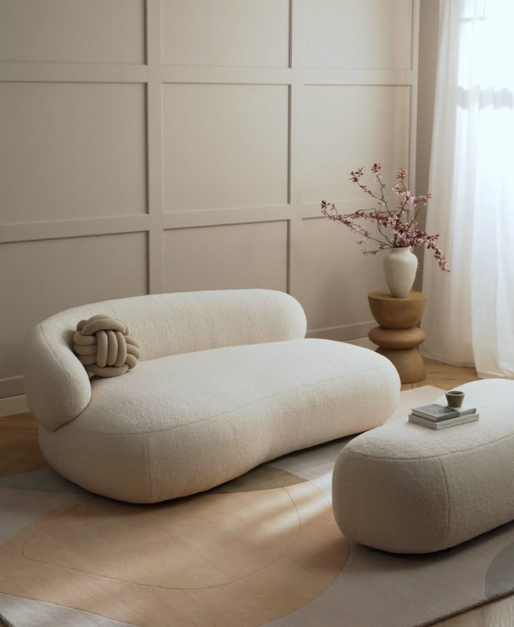 a white couch sitting on top of a wooden floor next to a vase filled with flowers