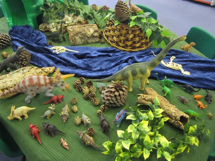 an assortment of toy animals and plants on a green table cloth covered with blue fabric