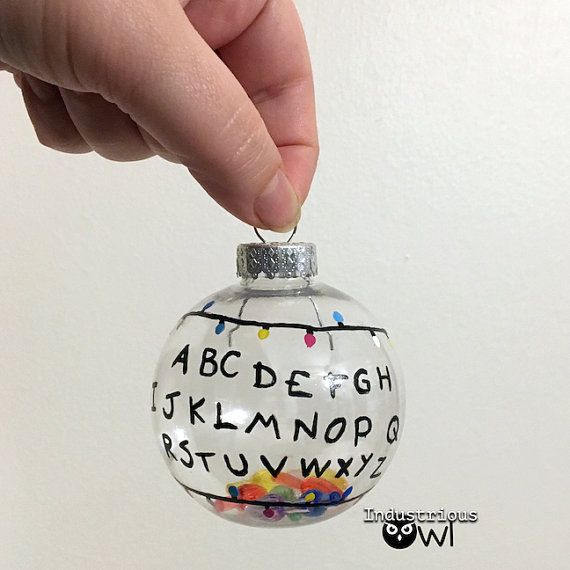 a hand holding a glass ornament with letters and numbers painted on the inside