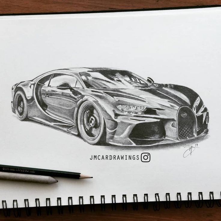 a pencil drawing of a bugatti car on top of a desk next to a pen