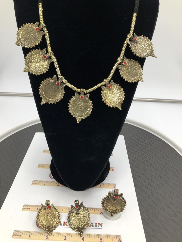 This complete vintage coin set includes a necklace, a pair of earrings, and a ring, is an epitome of tradition, as the design of the set is inspired by the Afghani Kuchi ornaments. The rusty gold toned set is embellished with dangling elements, adorned with intricate patterns and archaic motifs. The pair of earrings, coin shaped, complete the set in an astonishing manner, complimented by the antique ring in the identical design. You can pair this complete traditional set with any traditional or Vintage Medallion Jewelry For Festival, Vintage Medallion Jewelry For Festivals, Vintage Festival Medallion Jewelry, Handmade Ceremonial Jewelry For Festivals, Ceremonial Festival Metal Jewelry, Traditional Medallion Jewelry For Ceremonial Occasions, Traditional Handmade Medallion Jewelry, Antique Handmade Coin Necklace For Festival, Brass Coin Pendant Jewelry