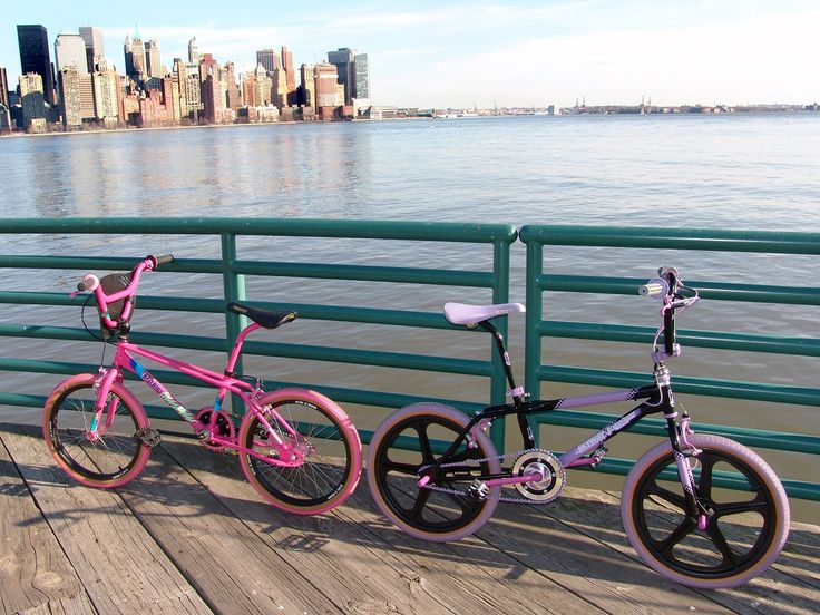 two bikes parked next to each other on a bridge near the water and city skyline